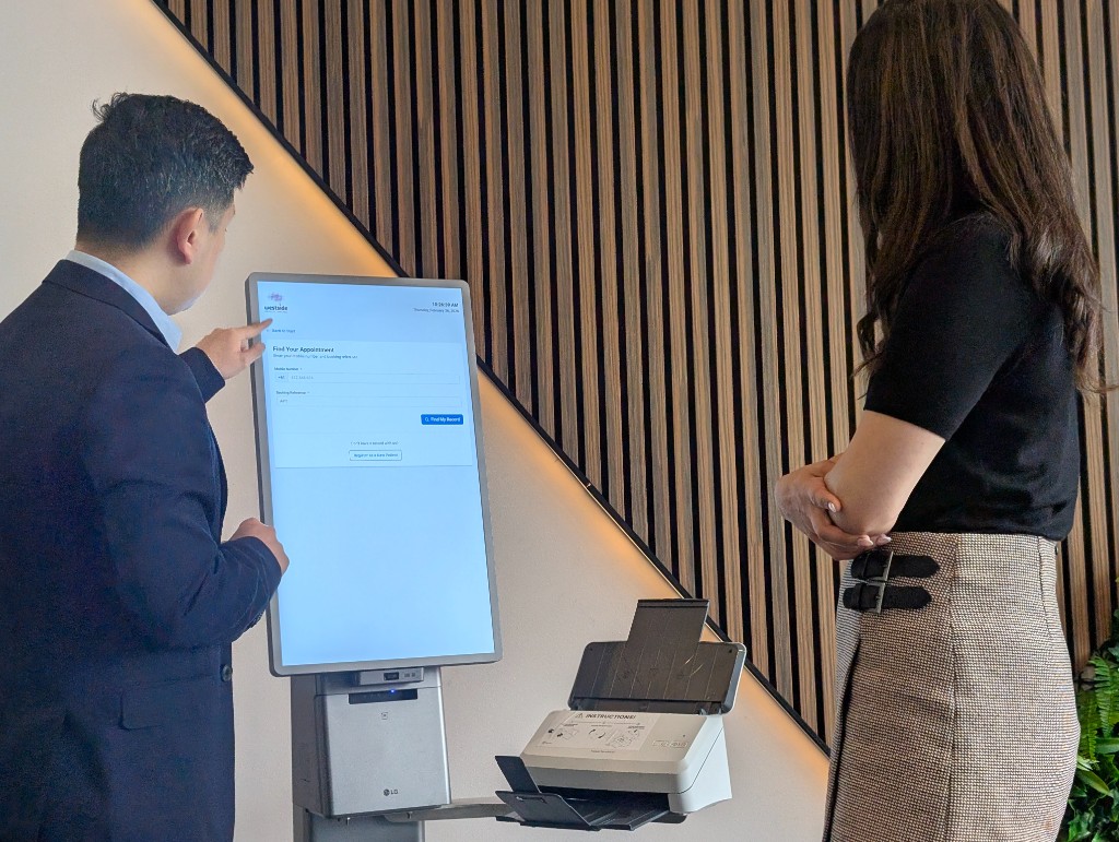Photo of kiosk screen showing appointment lookup with mobile number and reference fields